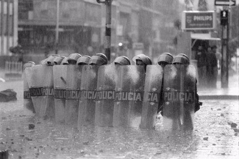پلیس ضد شورش در حالی که تظاهرات خشونت‌آمیز درست قبل از مراسم تشییع جنازه سیاستمدار چپ‌گرای ترور شده، جیمی پاردو لیل، در بوگوتا، کلمبیا، ادامه دارد، خود را سپر کرده‌اند، ۱۳ اکتبر ۱۹۸۷.