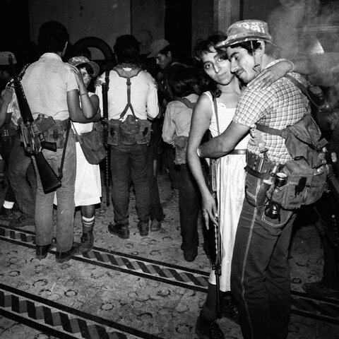شورشیان در جشن سال نو در کلیسایی قدیمی و متروکه در تنانسینگو، السالوادور، با اسلحه‌هایشان که روی شانه‌هایشان آویزان است، می‌رقصند، ۱ ژانویه ۱۹۸۵