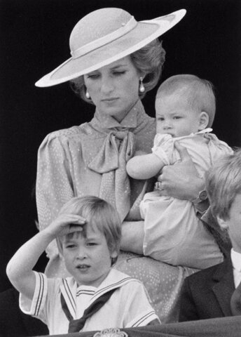 شاهزاده ویلیام، ولیعهد بریتانیا، در حالی که از بالکن کاخ باکینگهام در لندن، مراسم رژه رنگ‌ها را تماشا می‌کند، به همراه مادرش پرنسس دایانا، که شاهزاده هری را در آغوش گرفته است، سلام سلطنتی می‌دهد.