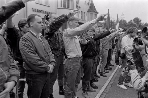 نئونازی‌ها در تظاهراتی در مقابل دفتر هلموت کهل، صدراعظم آلمان، در بن، دست‌های خود را به نشانه سلام نازی بالا می‌برند و خواستار آزادی یکی از رهبران خود می‌شوند، ۲۵ ژوئیه ۱۹۸۷