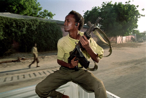 یک نوجوان سومالیایی در حالی که در صندلی عقب وسیله نقلیه نشسته و یک تفنگ تهاجمی حمل می‌کند، در موگادیشو، ۷ دسامبر ۱۹۹۲، از طریق هدفون به موسیقی گوش می‌دهد.