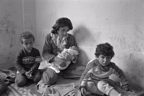 یک زن فلسطینی از اردوگاه پناهندگان عین الحلوه، نوزاد خود را در مدرسه‌ای در صیدا در آغوش گرفته است،