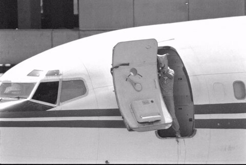 یک مرد مسلح با کیسه‌ای روی سرش، از درگاه هواپیمای ربوده شده خطوط هوایی ترانس ورلد (TWA) در فرودگاه بیروت، لبنان، در 20 ژوئن 1985، با تفنگ خودکار شلیک می‌کند.