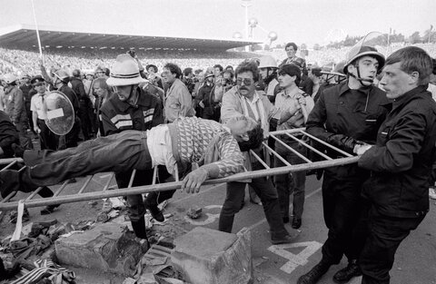 یک هوادار مجروح پس از فرو ریختن دیوار جایگاه تماشاگران پیش از شروع فینال جام باشگاه‌های اروپا بین لیورپول و یوونتوس در ورزشگاه هیسل، بروکسل، بلژیک، 29 مه 1985،